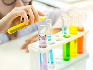 Closeup female scientist hand holding test tube contain colorful chemical intermediates