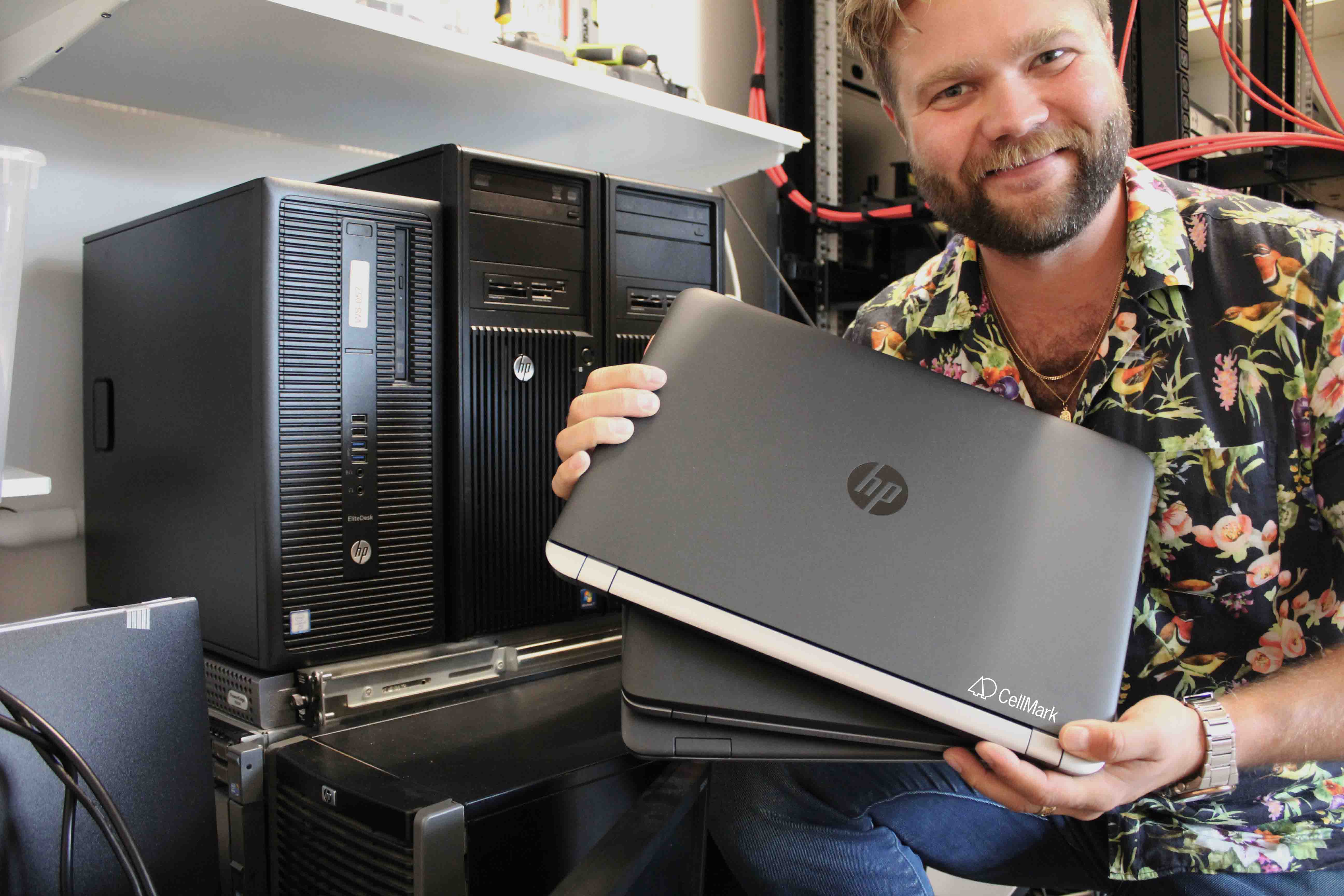 a bearded man is holding three laptops