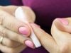 close-up of two hand removing pink nail polish from nail